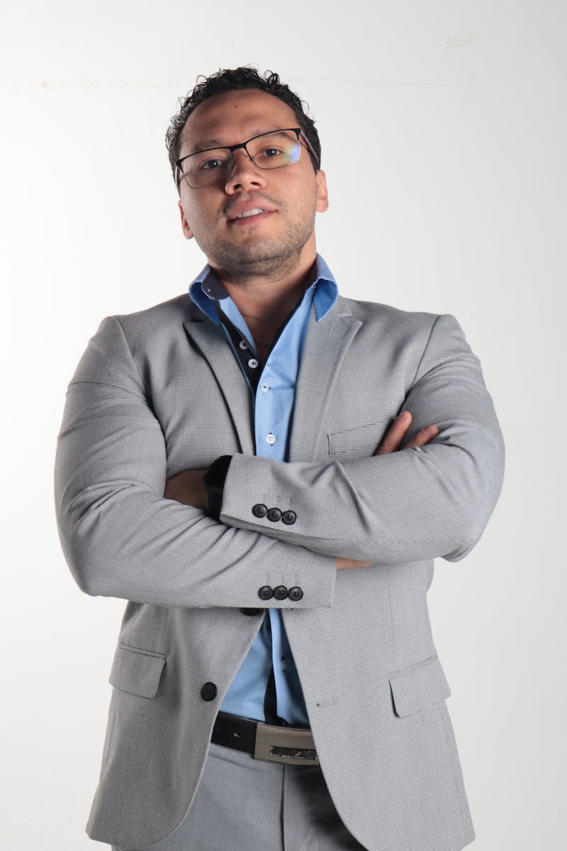 Portrait of a confident man in a gray suit with crossed arms against a white background.
