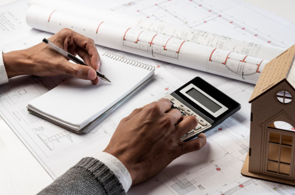 A property valuer examines a property's value guided by a model placed on top of the desk.